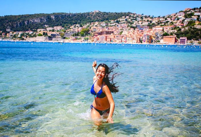 A woman in a blue bikini splashes in the ocean.