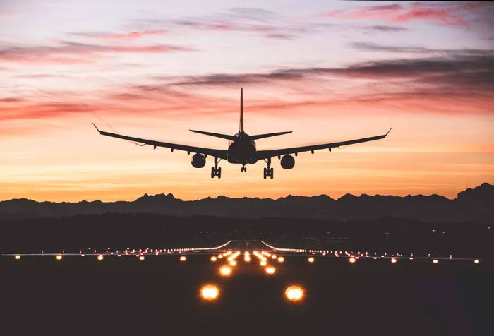 An airplane approaches the runway, illuminated by edge lights.