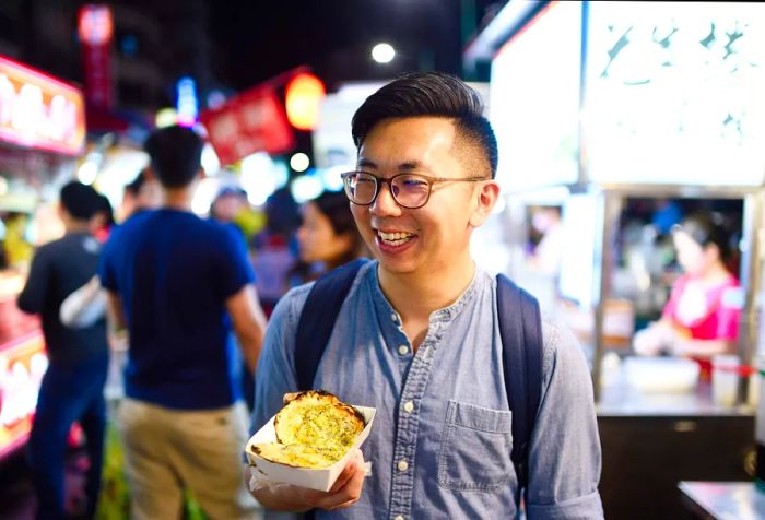 Cheerful man enjoying street food at a night market