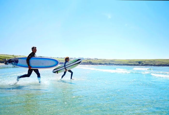 Surfers rush into the waves, their boards in hand, with lush landscapes framing the scene.