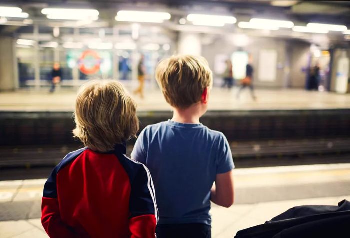 Two young boys wait for a train at a metro station.