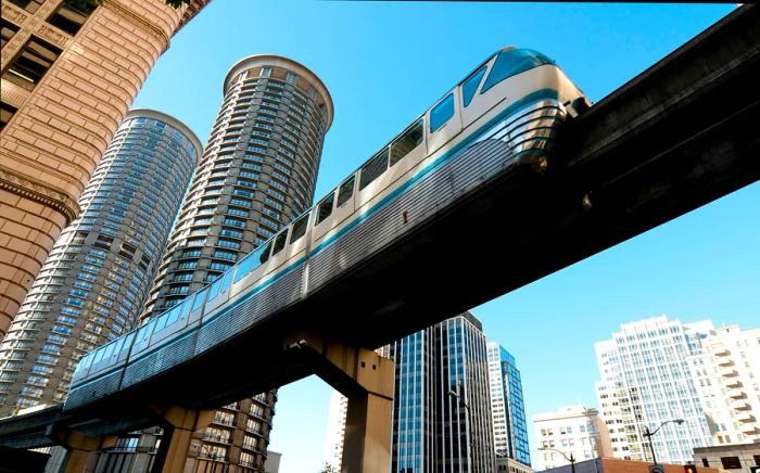 A monorail glides above a city filled with towering glass and steel structures.