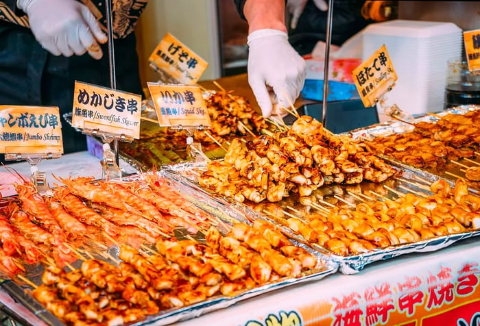 A vendor stall showcasing an assortment of grilled seafood skewers, each clearly labeled.