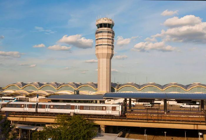 The control tower of Reagan National Airport stands tall above the vibrant terminal, while the nearby Washington Metro enhances urban connectivity, establishing a seamless transportation hub for travelers.