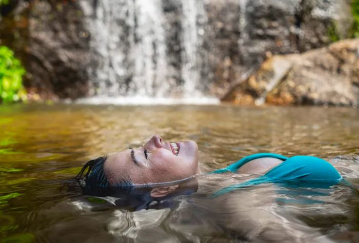 A relaxed woman drifts effortlessly in the water, completely immersed in the serenity of the moment.