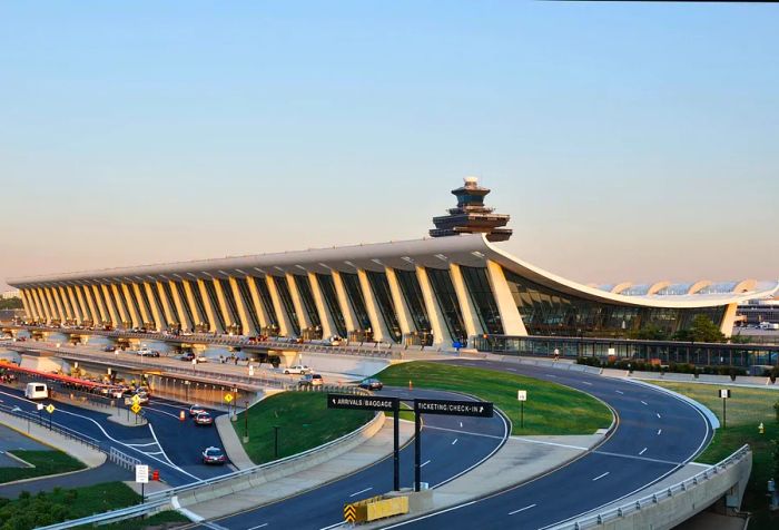 The main terminal at Washington Dulles International Airport is known for its striking curved architecture and large glass windows, accessible via a network of approach roads.