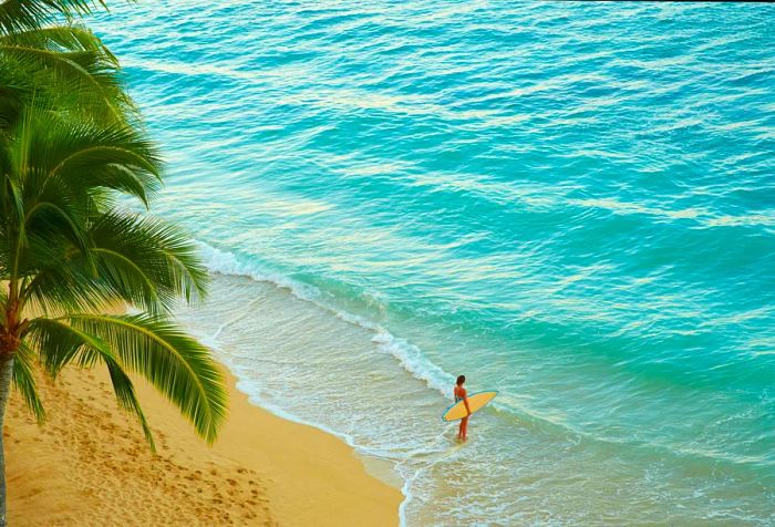 A woman stands on the beach with her surfboard, feeling the waves crash against her feet.