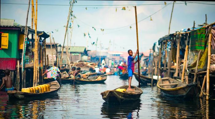 A young boy paddling a canoe in Makoko Stilt Village, Lagos