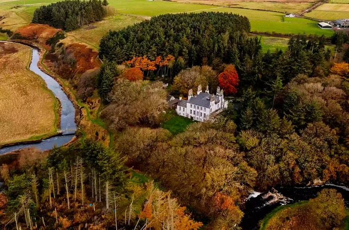 Aerial view showcasing a hotel and rivers in Scotland, adorned with autumn foliage.