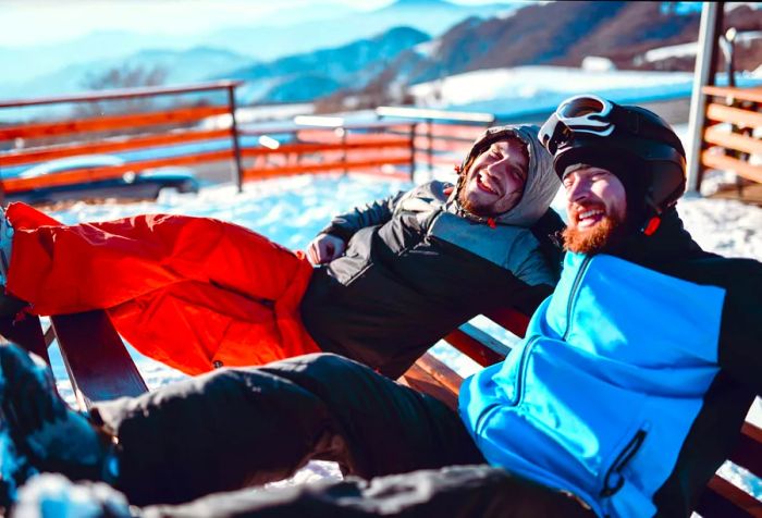 A gay couple sharing a warm embrace after skiing on the mountain.