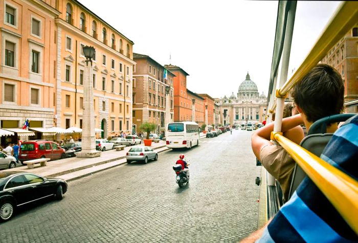 A bus tour group traveling along the road towards St. Peter's Basilica.