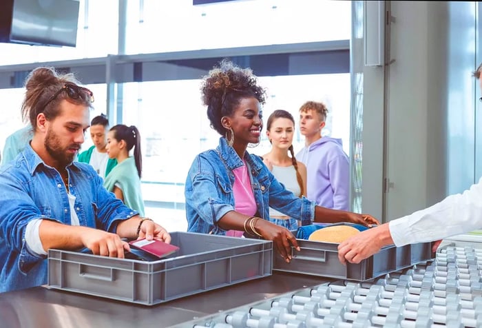 Diverse group of travelers navigating through airport security screening.