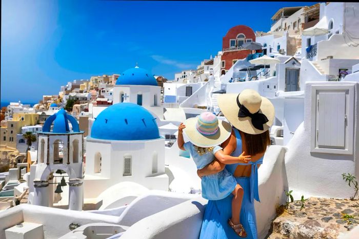 A mother and her daughter admiring the iconic whitewashed buildings of Oia.