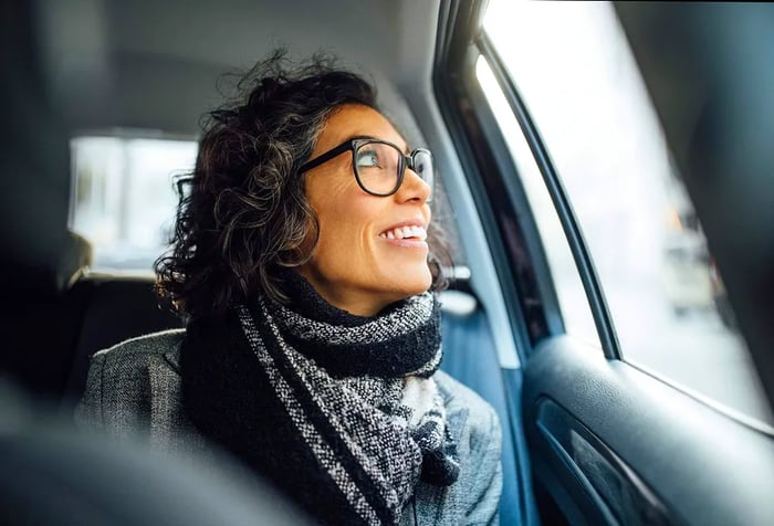 a woman with glasses gazing out the window of a taxi