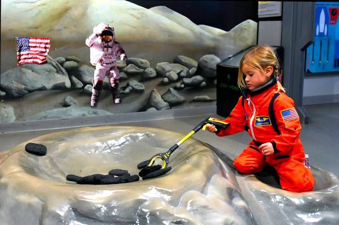 A three-year-old girl collecting moon rocks during her AstroTot Training at the Denver Museum of Nature & Science