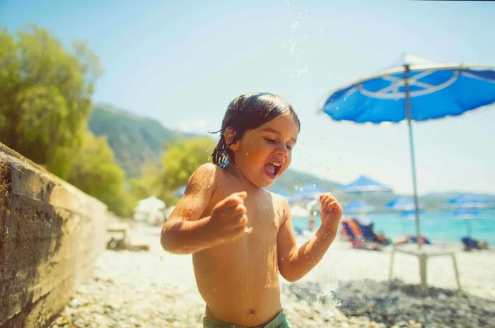 A young boy rinsing off sand at a Greek beach