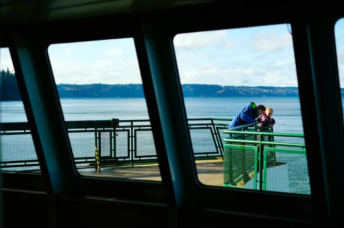 Two siblings enjoy the view from the deck of a passenger ferry as it navigates through Puget Sound, Seattle