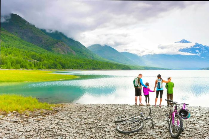 Family riding bicycles by a lake in Alaska