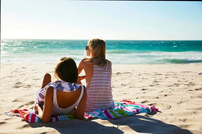 A group of friends and couples enjoying a day at the beach, dressed in shorts and casual tops.