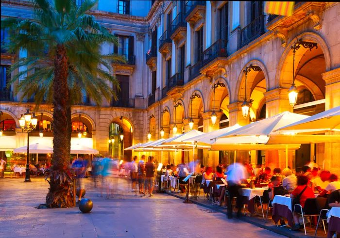 People enjoy their meals at outdoor restaurant tables in the evening