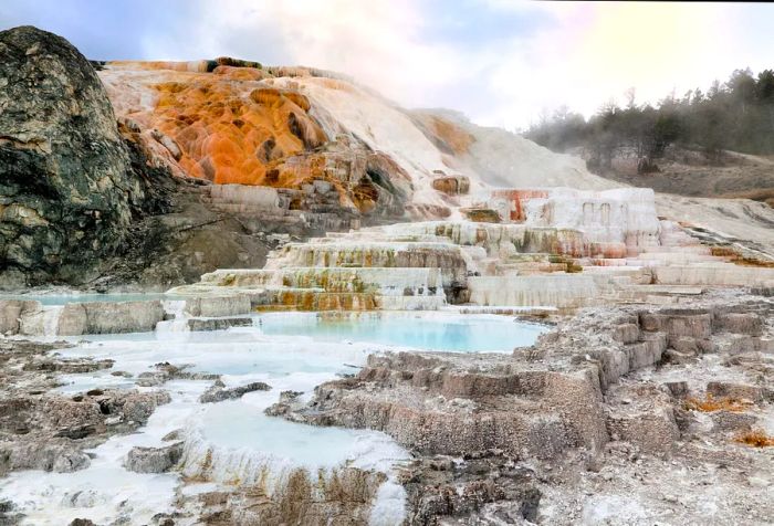 A hillside adorned with tiered rock formations covered in white mineral deposits.