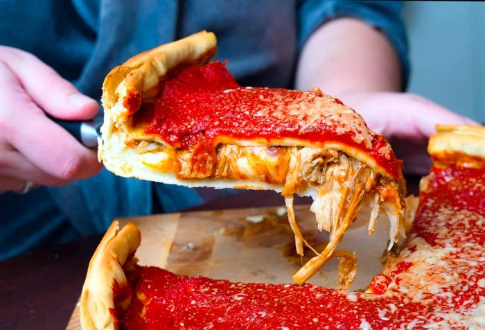 A woman's hands expertly slice into a delicious Chicago-style deep-dish pizza, overflowing with rich Italian cheese, savory tomato sauce, and tender beef mince.