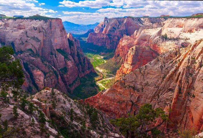 A breathtaking rocky mountain range stretches across the horizon, with a charming valley nestled below, enveloped by towering cliffs.