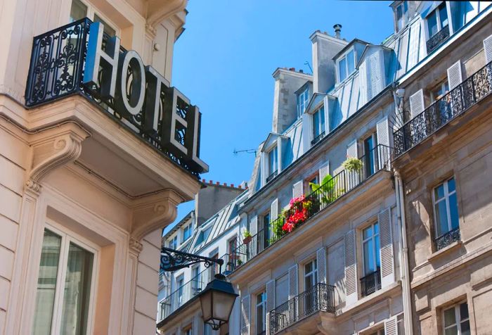 A hotel sign displayed on the ornate wrought iron railing of a balcony.