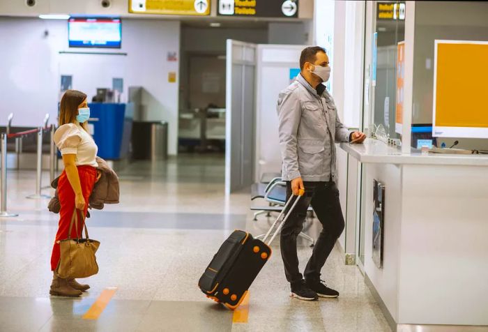 Passengers wearing face masks checking in for their flight at an airport.