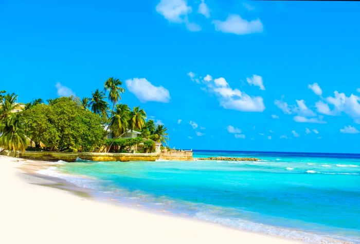 A picturesque beach view showcasing soft white sands and crystal-clear aquamarine waters beneath a bright blue sky.