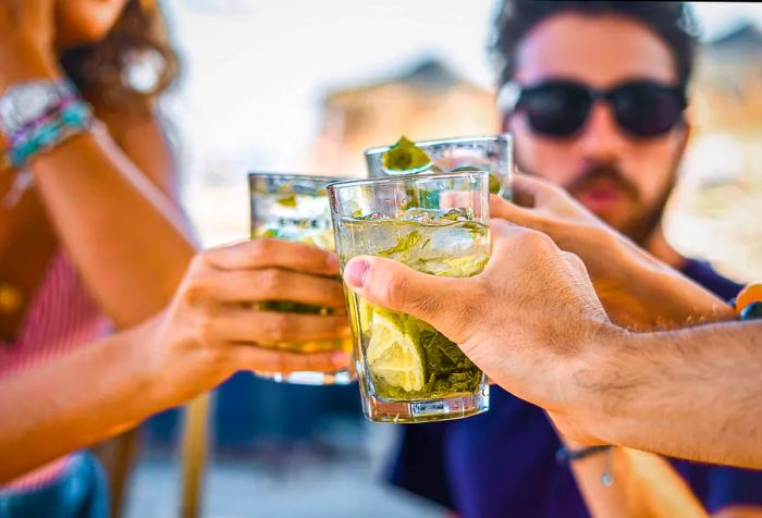 Hands raising glasses filled with colorful cocktails in a toast.