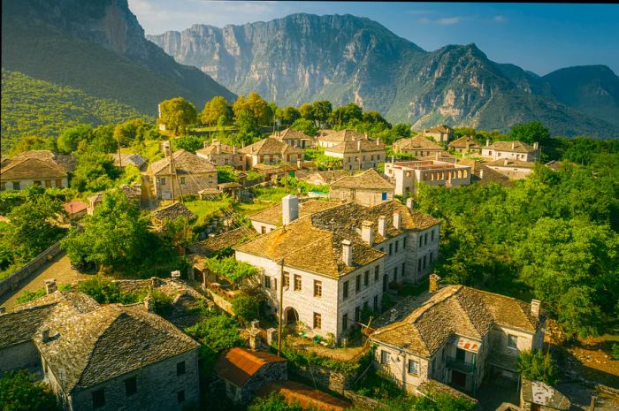 The village of Papingo and Mount Tymfi in Zagori (or Zagorochoria) at the Pindus Mountains, Greece, surrounded by lush trees and towering mountains.