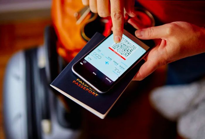 A traveler checks the QR code for their flight on their mobile device, positioned atop their passport.