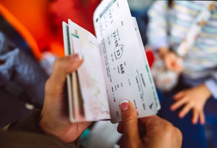 A close-up view of a female traveler examining her boarding pass and passport at the airport boarding gate.