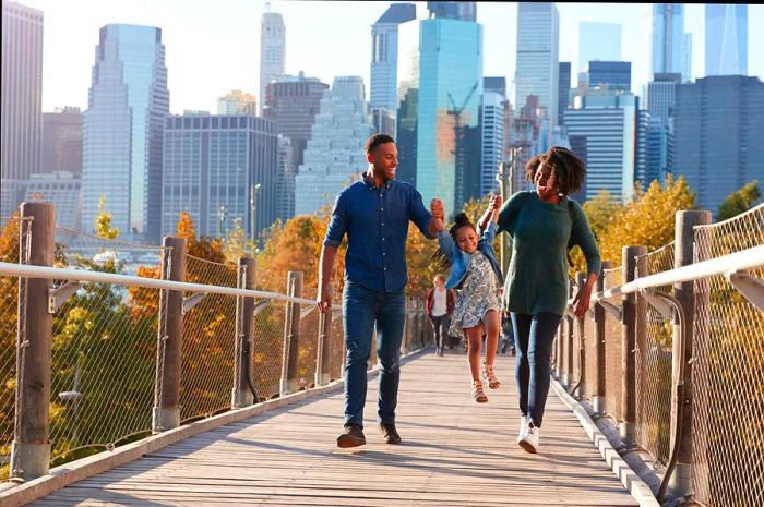 A young family with their daughter strolling along a footbridge in New York