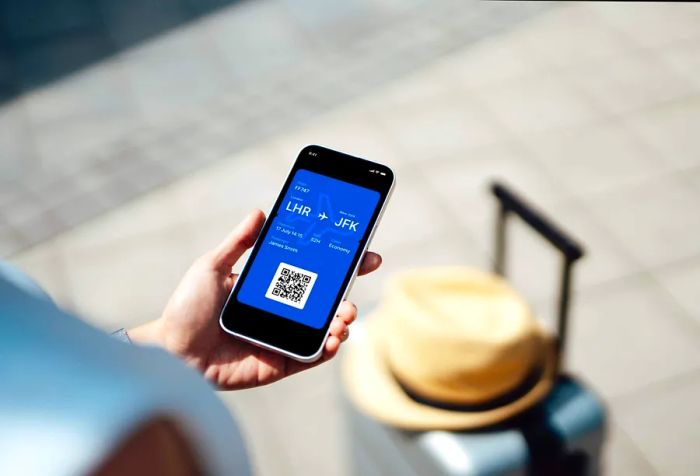 A young woman checks her electronic flight ticket on her mobile device from an over-the-shoulder perspective. She's using a mobile boarding pass to check in.