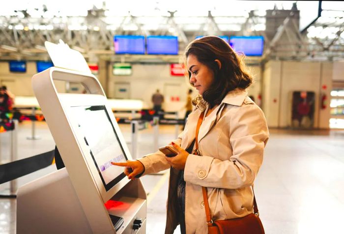 A woman interacts with a modern self-service kiosk at the airport.