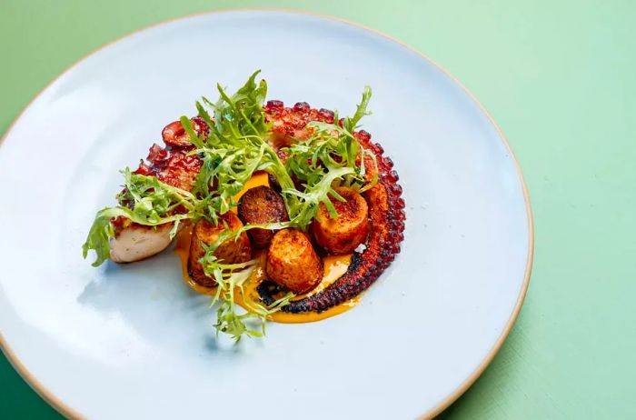 A dish featuring octopus and scallops accompanied by greens at Bar Le Côte