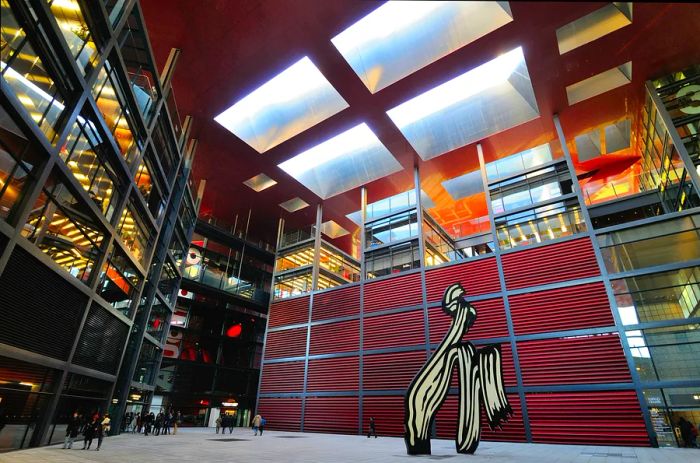 Visitors in the interior courtyard of Madrid's Reina Sofia museum, admiring a tall black-and-white sculpture by Roy Lichtenstein