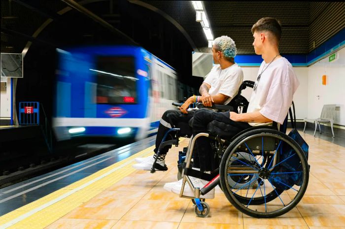 A wide-angle view of young male friends in wheelchairs waiting for the train at the station