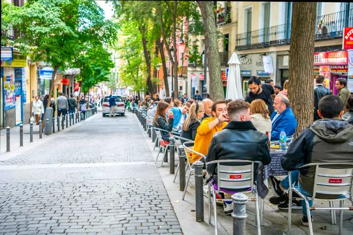 Diners enjoying their meals on the terrace in the vibrant Lavapiés neighborhood in central Madrid.