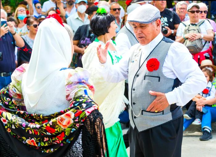 Two individuals in traditional attire perform a dance at a festival