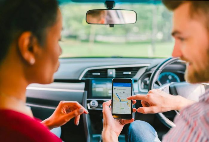 Driver demonstrating the navigation app on his smartphone to a passenger.