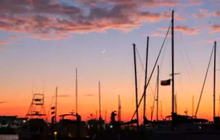 Sunset and moonrise over the harbor filled with boats in Port Aransas, Texas