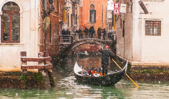 A gondola glides through a canal as snow falls in Venice, Italy.