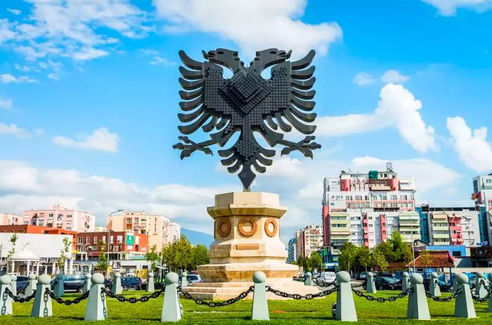 Majestic Coat of Arms of Albania Statue in a roundabout in Tirana’s city center beneath a vibrant summer sky with fluffy clouds, Tirana, Capital of Albania, Southeastern Europe.