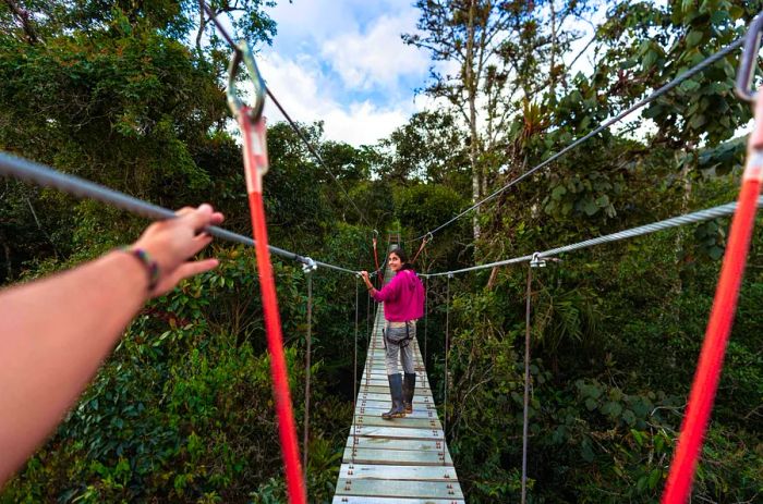 A woman navigates a hanging rope bridge in Costa Rica, Central America.