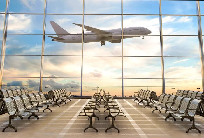 An airplane flies by the expansive glass windows of the terminal.