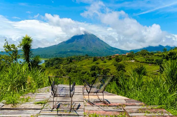 Two lounge chairs on a deck with a view of Volcán Arenal in La Fortuna, Costa Rica.