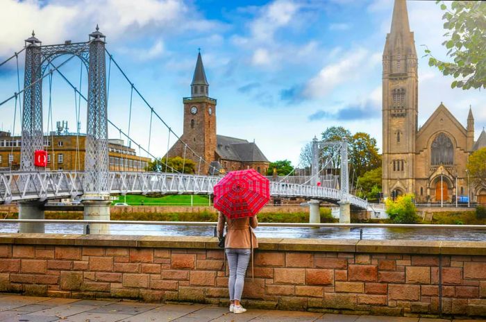 A tourist with a red tartan umbrella gazes at the view of a church